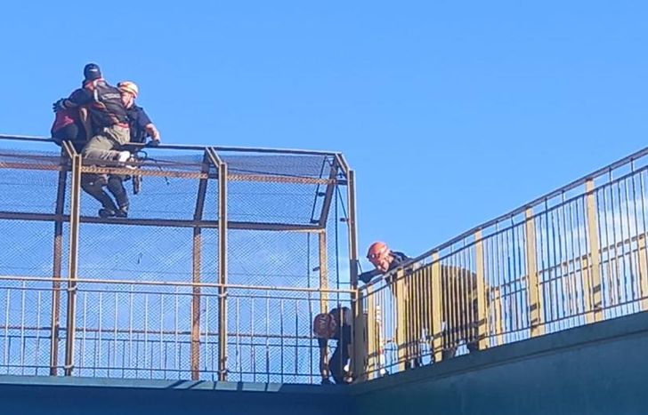 Los bomberos se encargaron de llegar hasta la persona que estaba en el puente peatonal para salvarlo.