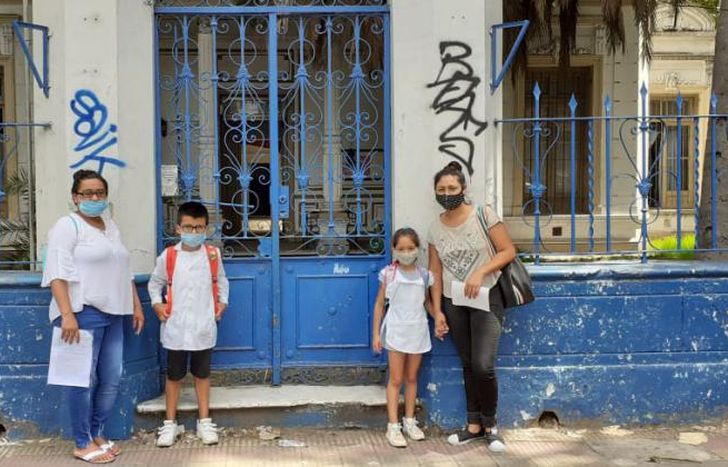 Dos chicos con sus madres en la puerta de la Escuela N° 9.