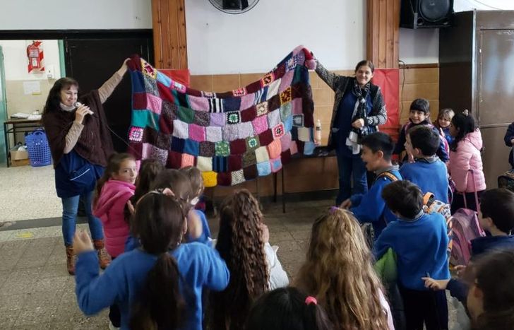 Presentando a los alumnos de primario, una de las mantas terminadas que pronto será donada.