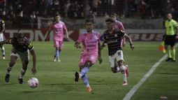 Sosa despeja mientras Vella lo sigue de cerca.