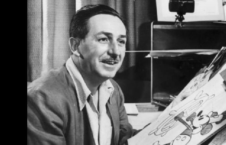 Mr Walt Disney sits at his drawing board in his studio, drawing a sketch of Mickey Mouse
