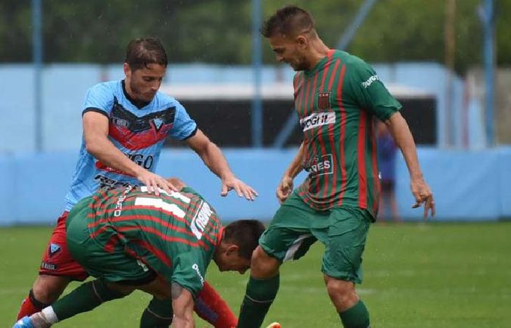 Juan Manuel Olivares intenta superar la doble marca del rival. Poco fútbol y mucha agua en Adrogué.