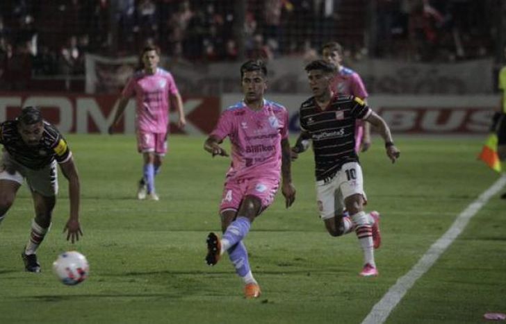 Sosa despeja mientras Vella lo sigue de cerca.
