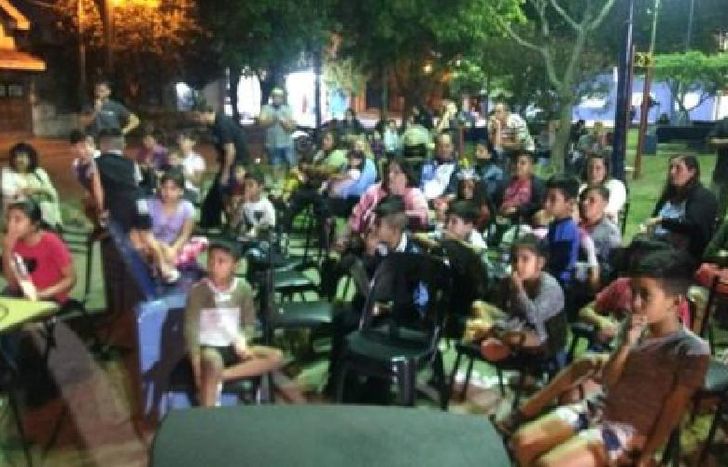 grandes y chicos en la plaza disfrutando del film Coco.