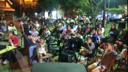 grandes y chicos en la plaza disfrutando del film Coco.