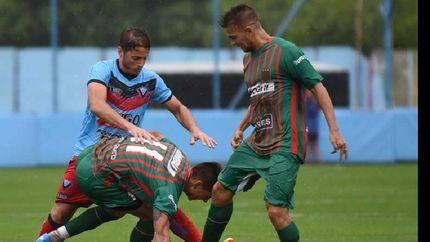 Juan Manuel Olivares intenta superar la doble marca del rival. Poco fútbol y mucha agua en Adrogué.