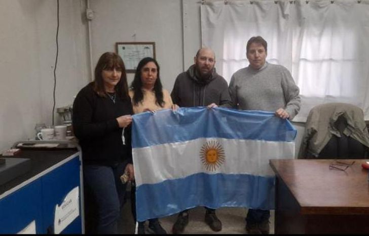 José, junto a los directivos de la escuela. La bandera, lista para flamear.